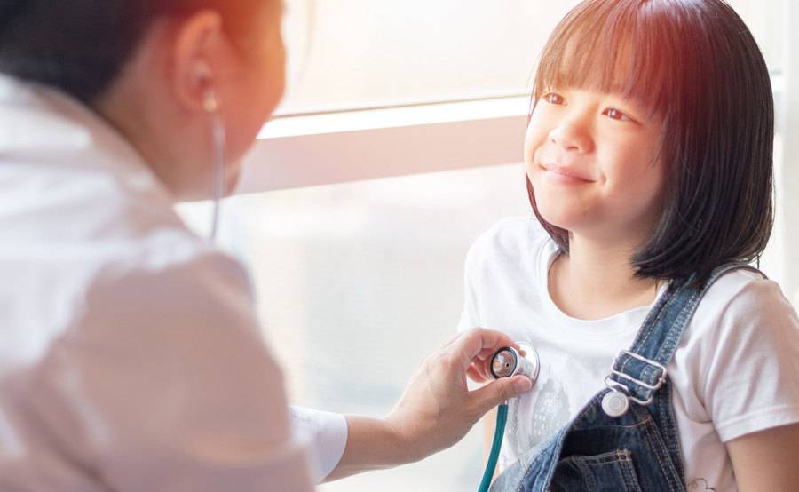 A physician examines a little girl, exemplifying the quality care accessible to members of Qualcomm Premier Plans, a Scripps ACO products.