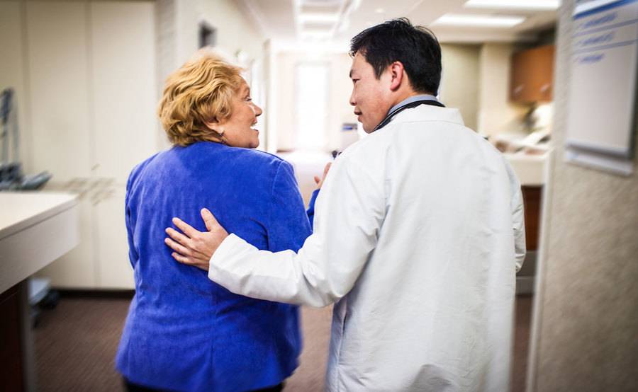 A doctor walks down the hall with a Medicare patient, illustrating an interaction common to providers who participate in the Medicare Shared Savings Program.